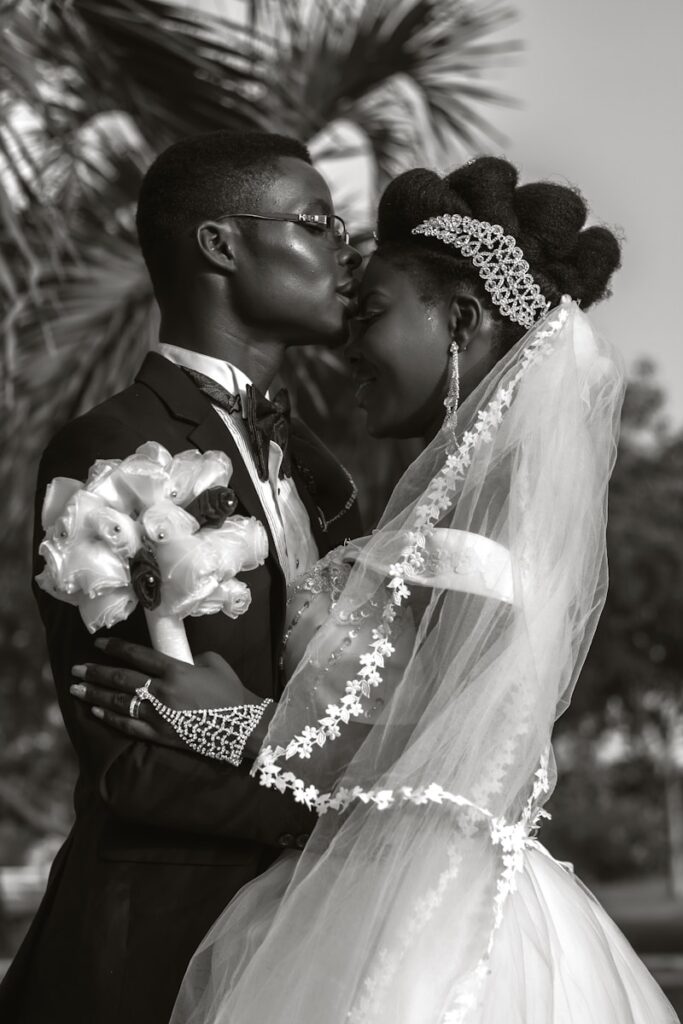 a bride and groom kissing in front of a palm tree